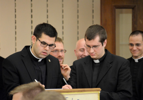 Seminarians Shane Nunes ('18) and Frank Furman ('18) leave notes of thanks in a book for Msgr. Checchio.